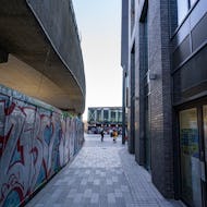 A walkway between graffiti and a modern office building